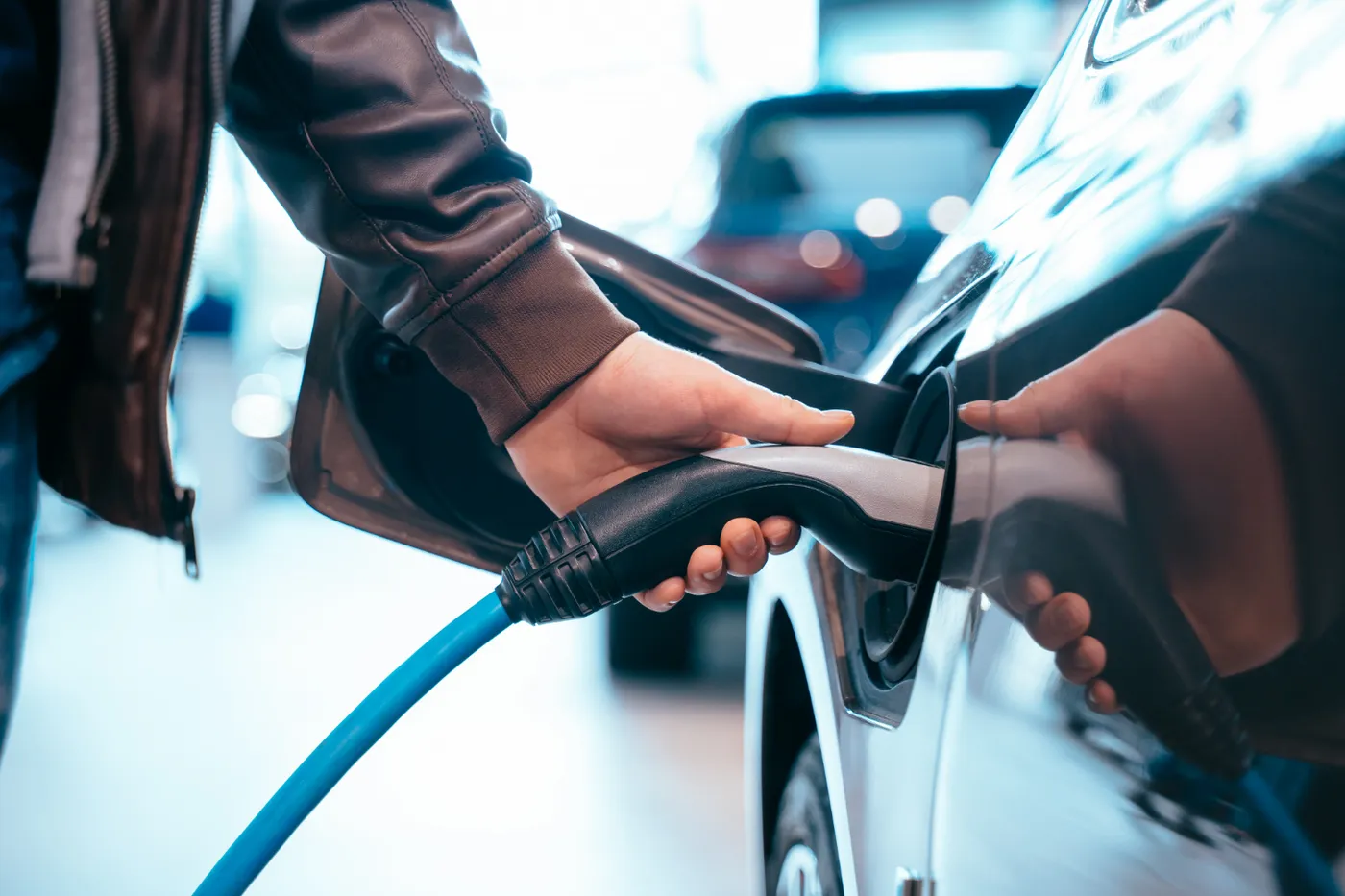 Mano conectando el cargador a un coche eléctrico